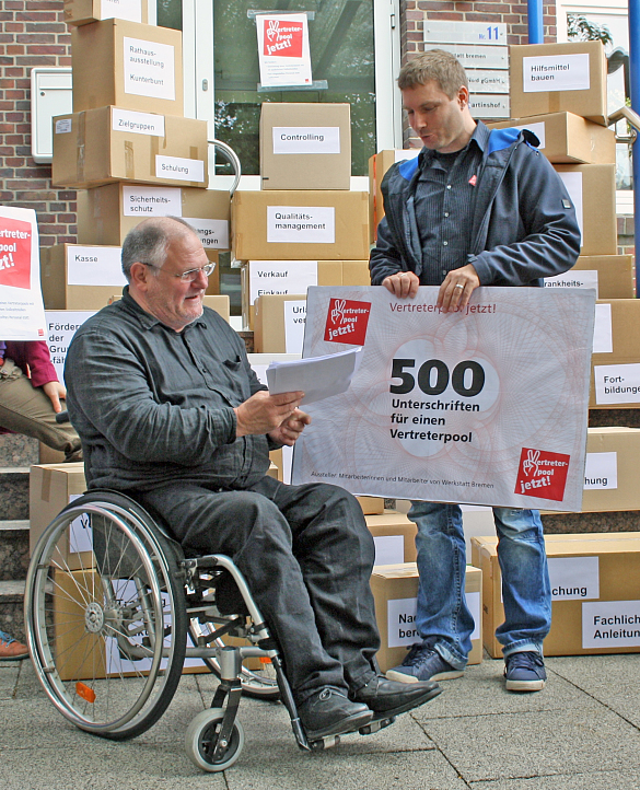 Jörn Kroppach überreicht einen "Scheck" mit 500 Unterschriften Herrn Staatsrat Frehe