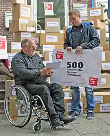 Jörn Kroppach überreicht einen "Scheck" mit 500 Unterschriften Herrn Staatsrat Frehe