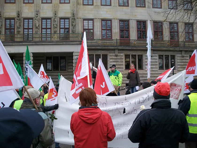 Beschäftigte mit Fahnen und Transparenten auf dem Platz vor der Senatorin für Finanzen