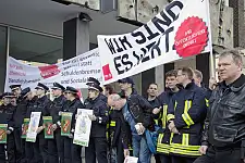 Polizisten und Feuerwehrmänner mit Transparenten vor dem Eingang der Bremischen Bürgerschaft