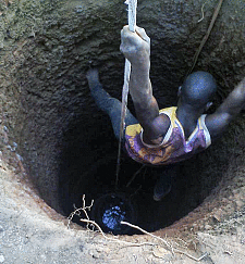 Ein Arbeiter hangelt sich am Seil in die tiefen Brunnen