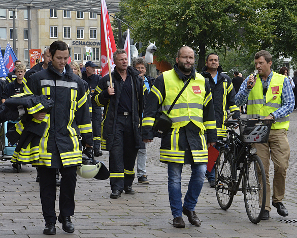 Feuerwehrbeamtinnen und Feuerwehrbeamte laufen zum Rathaus