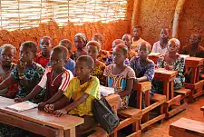 Kinder sitzen dichtgedrängt an Schulbänken