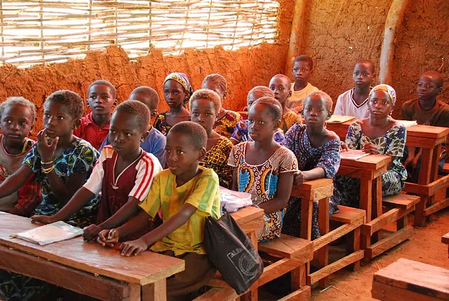 Kinder sitzen dichtgedrängt an Schulbänken