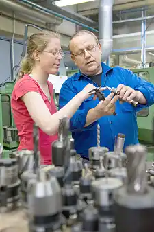 Einer Beschäftigten wird erklärt, wie ein Schaftfräser funktioniert