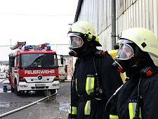 Zwei Feuerwehrbeamte in Schutzkleidung mit Löschfahrzeug