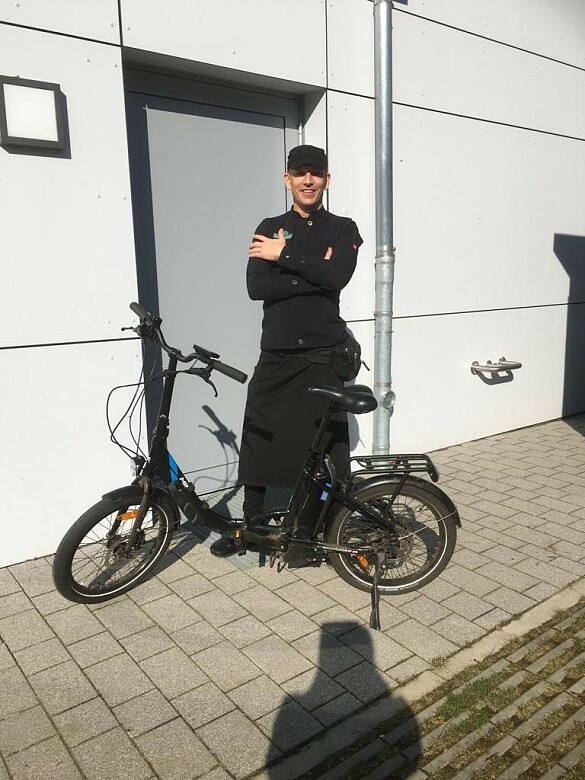 Friedrich Peters in Arbeitskleidung mit seinem E-Fahrrad