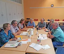 7 Personen sitzen an einem Tisch