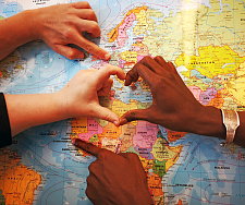 vier verschiedene Hände bilden ein Herz auf einer Landkarte