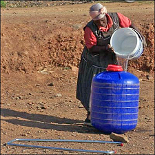 Frau gießt Wasser in einen großen Wasserbehälter, Hipporoller genannt