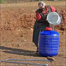 Frau gießt Wasser in einen großen Wasserbehälter, Hipporoller genannt