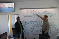 Ein Mann zeigt einem anderen etwas auf einem großen Plan der Häfen.