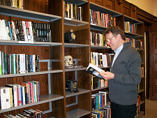 Kollege Bernd Krause steht lesend vor einem Bücherregal