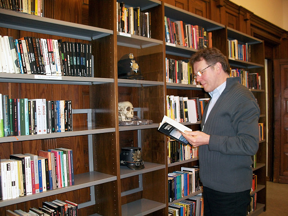 Kollege Bernd Krause steht lesend vor einem Bücherregal