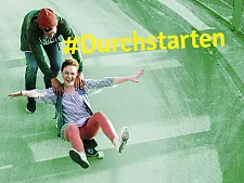 zwei Jugendliche, einer sitzt auf einem Skateboard