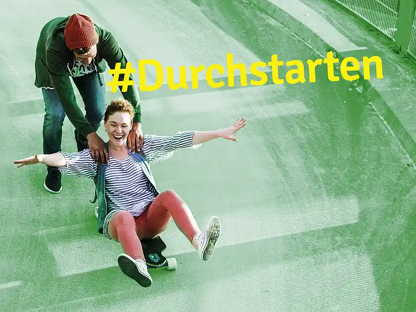 zwei Jugendliche, einer sitzt auf einem Skateboard