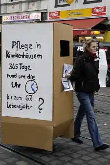 Kollegin auf Demonstration mit Pappkarton zum Thema Rente mit 67