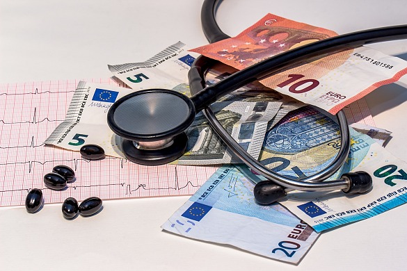 Bild zeigt einige Tabletten, ein Stethoskop und Banknoten
