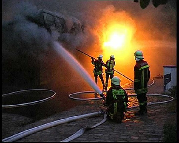 Feuerwehrmänner beim Löschen eines brennenden Hauses