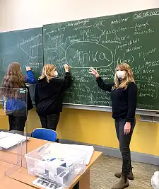 Linda Stibal im Klassenraum. Sie zeigt etwas an der Tafel.