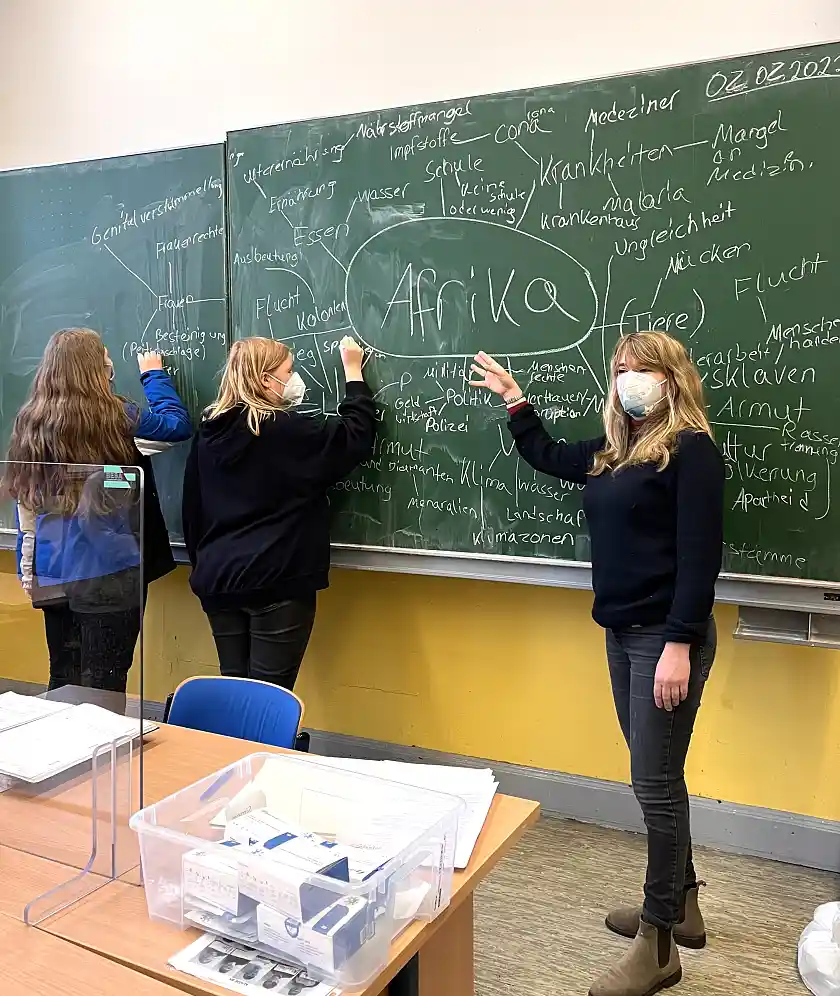 Linda Stibal im Klassenraum. Sie zeigt etwas an der Tafel.