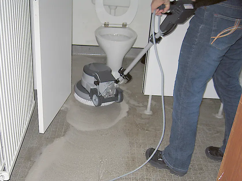 Raumpflegerin mit neuer Reinigungsmaschine in der Toilette