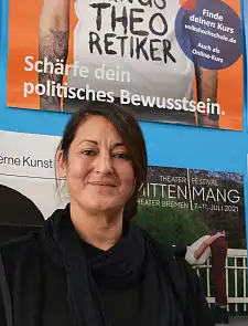 Nilgün Ozan vor einem Plakat mit der Aufschrift: Schärfe dein politisches Bewusstsein.