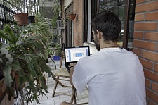 Ein junger Mann arbeitet in einem Wintergarten am Notebook