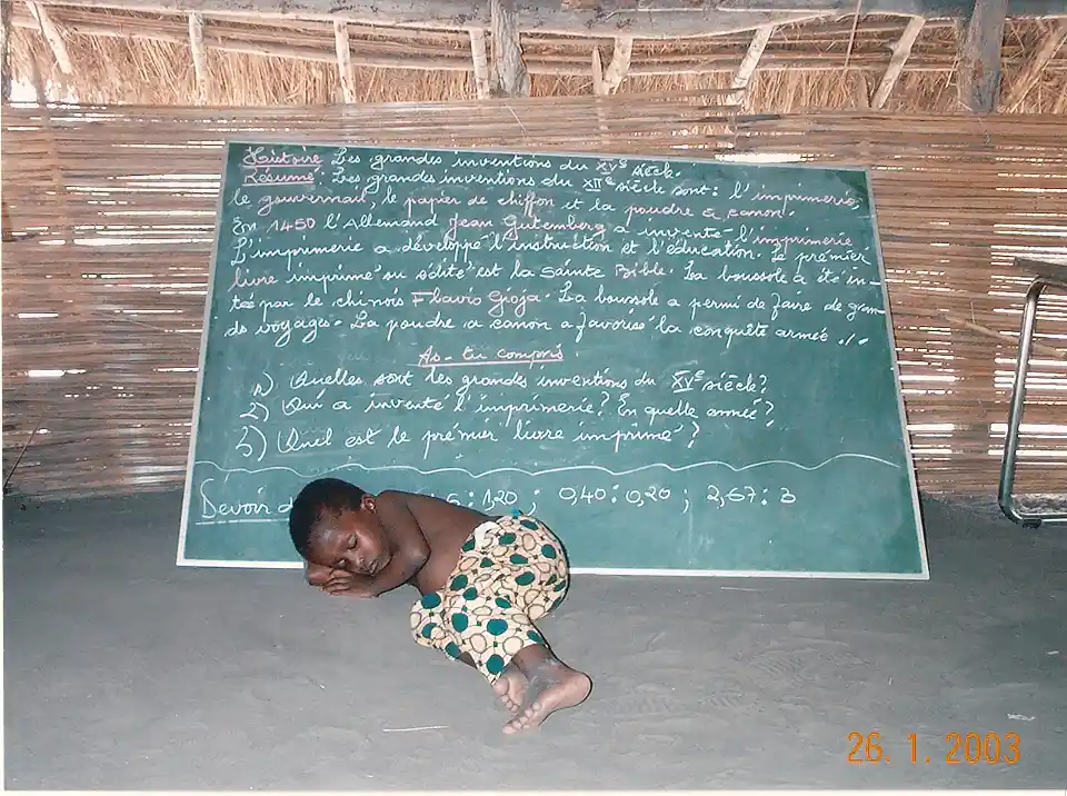 Ein kleiner junge schl&auml;ft vor einer Tafel