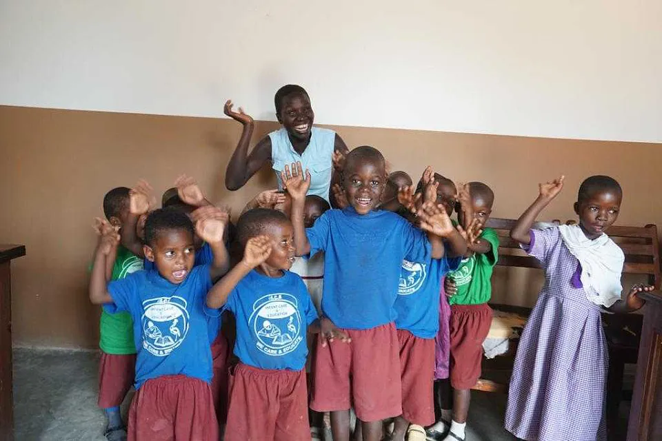 Eine Gruppe von Kindern mit ihrem Lehrer. Sie winken in die Kamera.