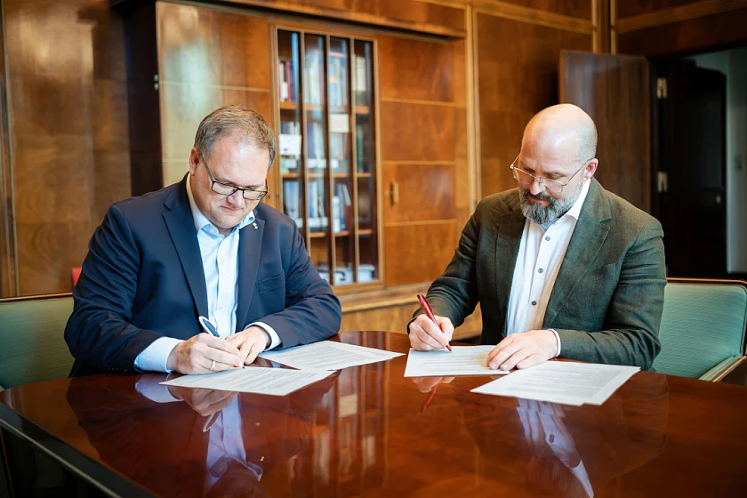 Der Senator für Finanzen, Bürgermeister Björn Fecker, und der Vorsitzende des Gesamtpersonalrats, Lars Hartwig, sitzen an einem Tisch und unterzeichnen die Dienstvereinbarung